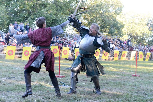 Two people dressed like knights fight with swords
